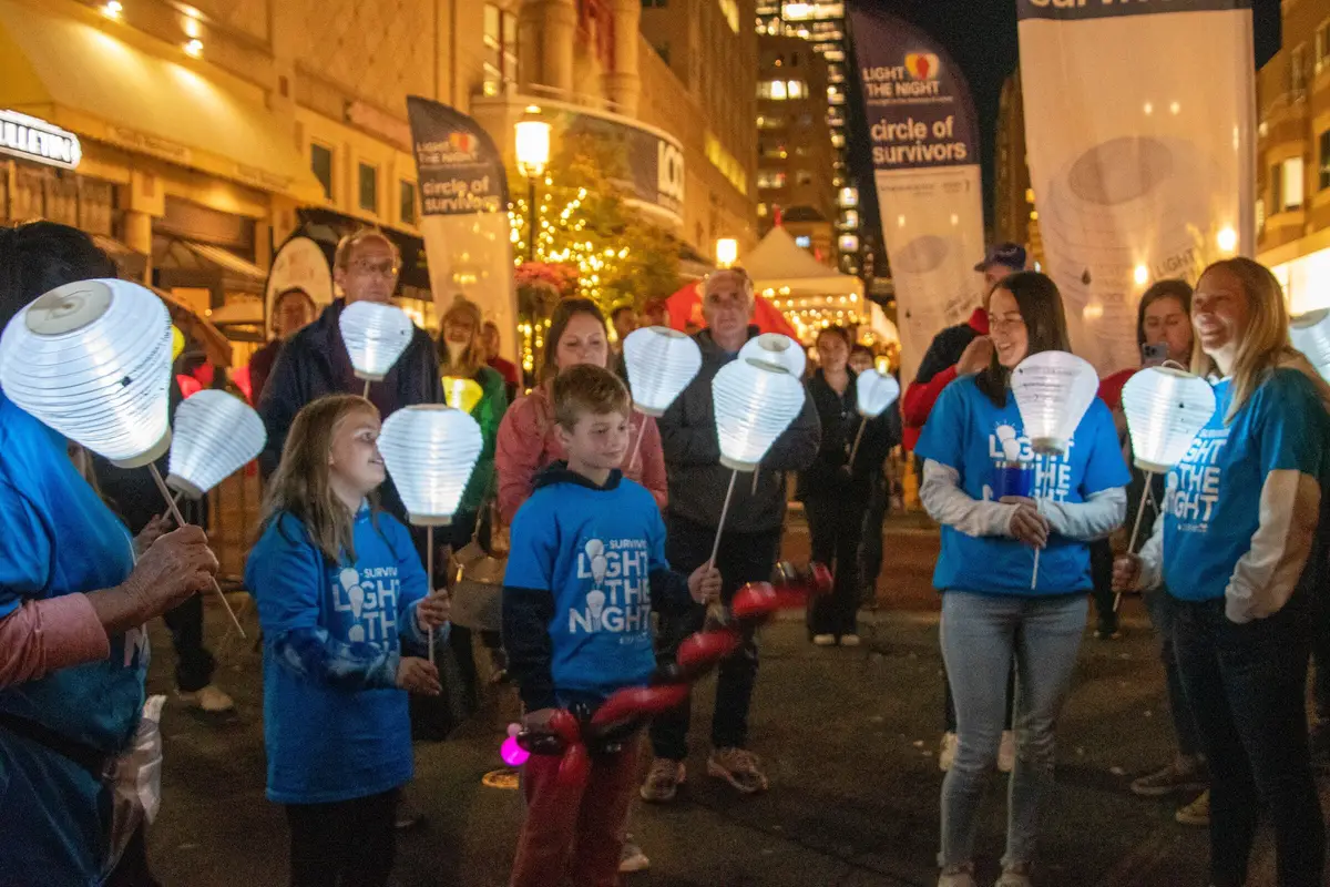 Crowd with glowing lanterns at a Light the Night charity walk