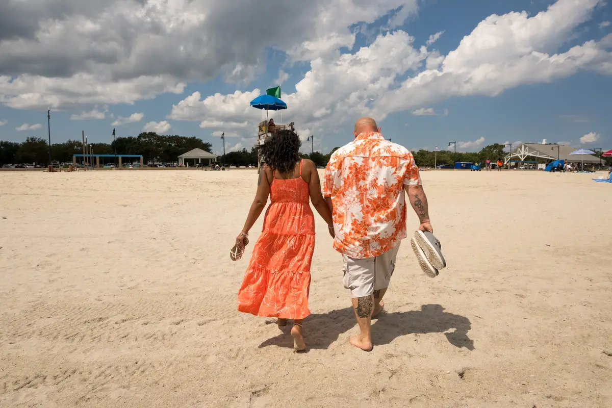 Couple walking on the beach, seen from behind