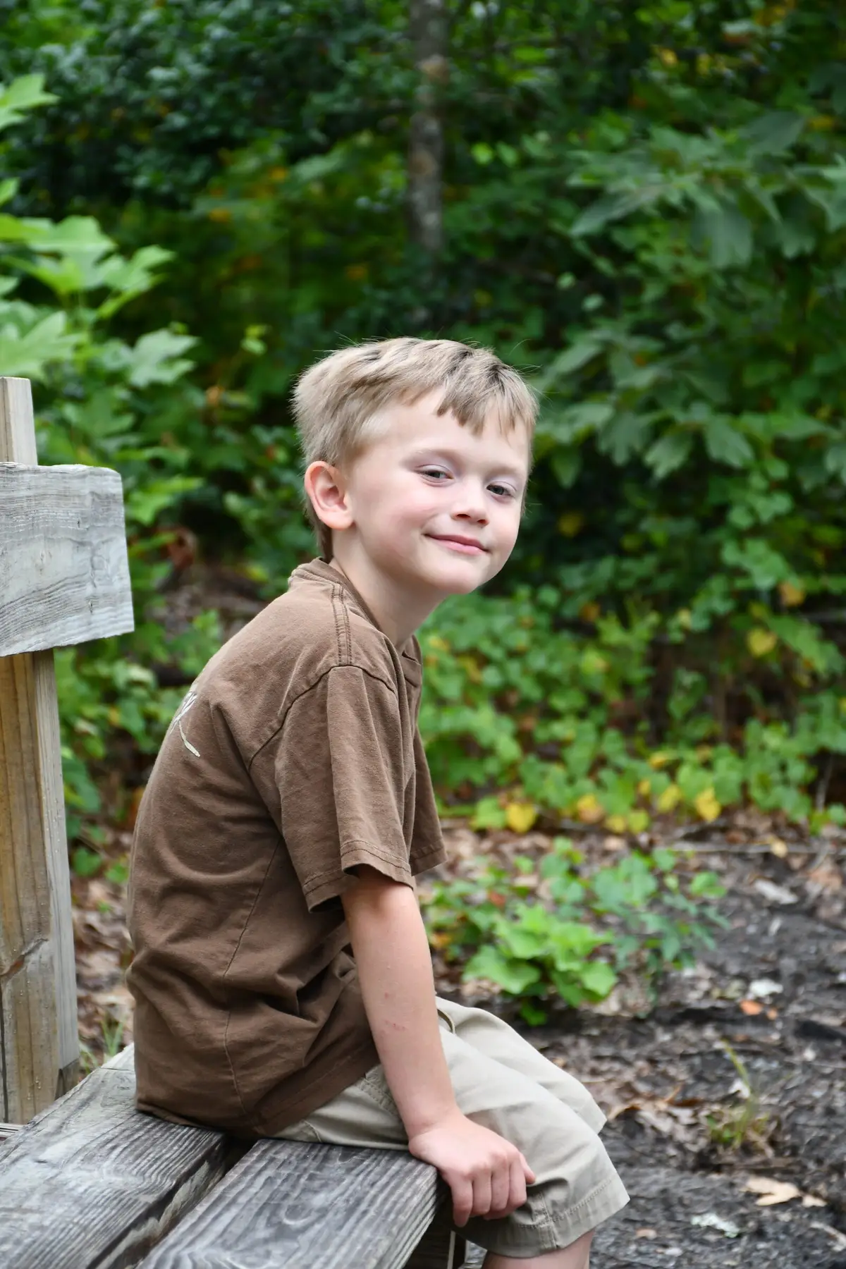 Two boys seated together on a log in the woods