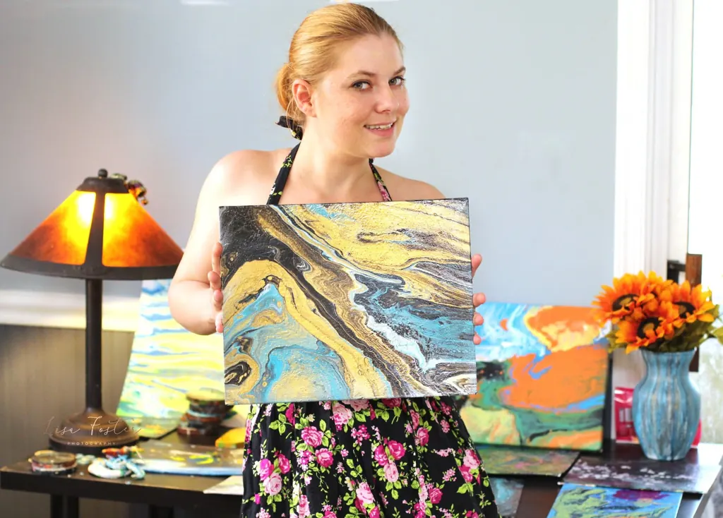 Artist holding her colorful pour painting
