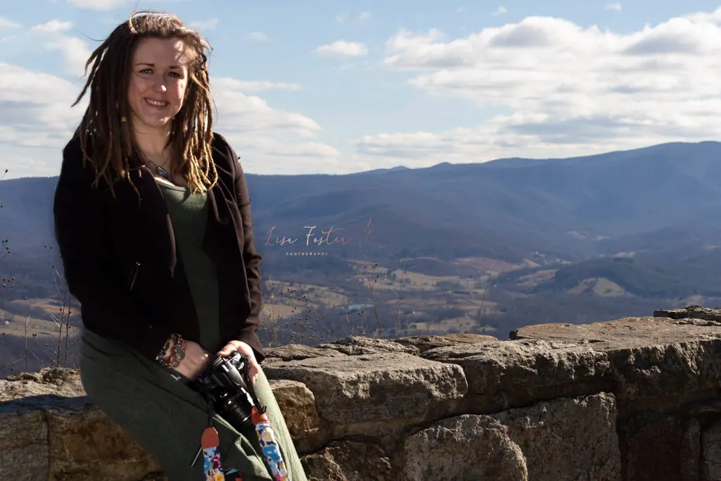 Woman seated on a stone wall above a mountain valley