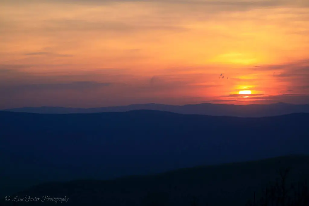 Layered blue ridges under an orange sunset