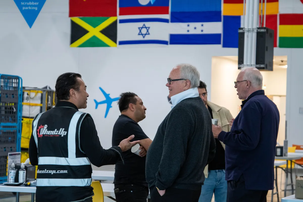 Business owners talking with a client inside a warehouse with international flags