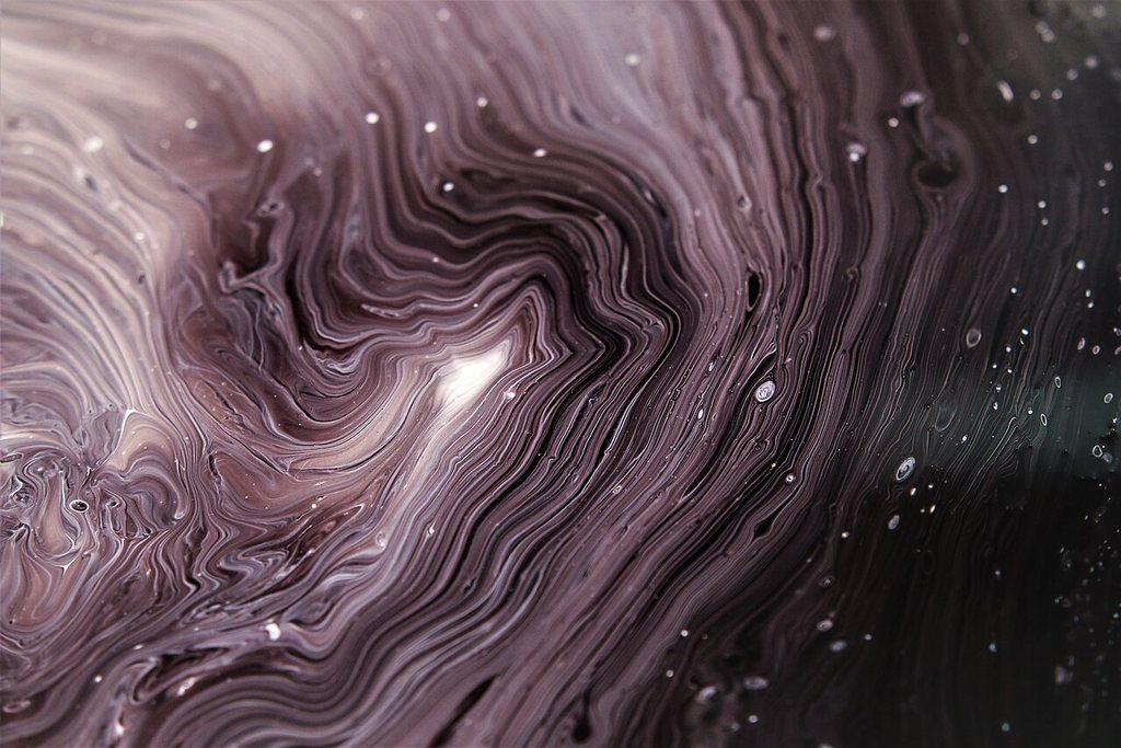 Close-up of swirling poured acrylic paint in plum, white and black