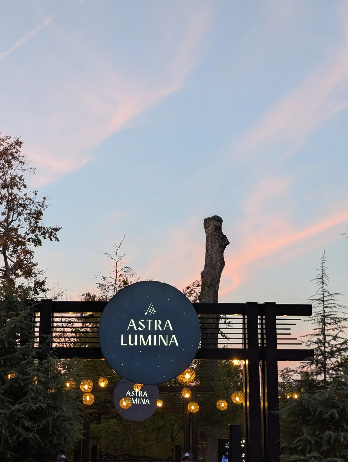 An archway lit blue and purple at dusk, with the words Astra Lumina by Moment Factory