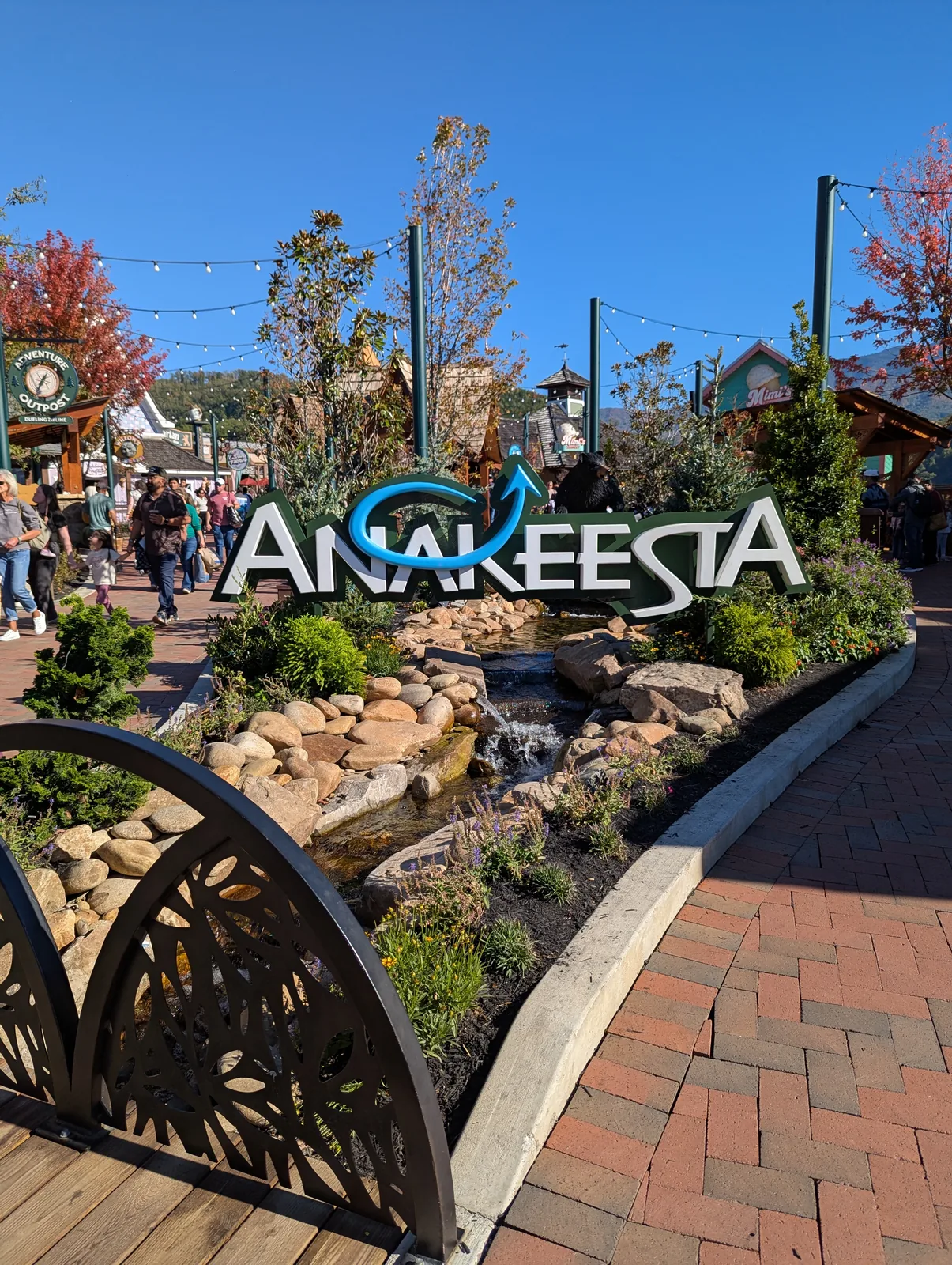 The Anakeesta entrance sign in dark letters, with yellow and orange mums and pumpkins planted in front