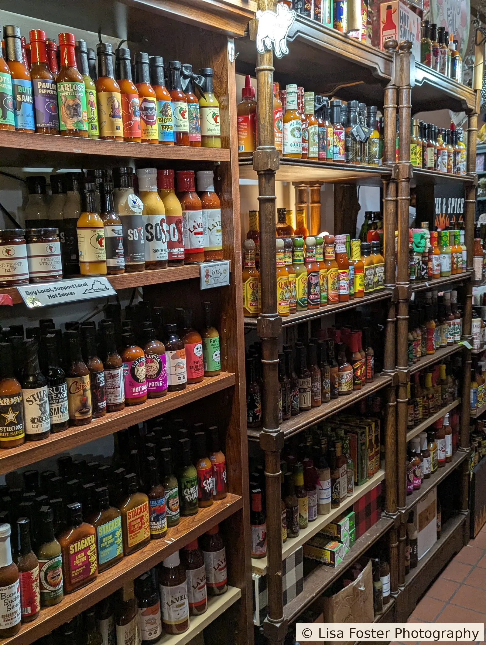 A wall of hot-sauce bottles at The Apple House, under a shelf that reads Buy Local, Support Local Hot Sauces.
