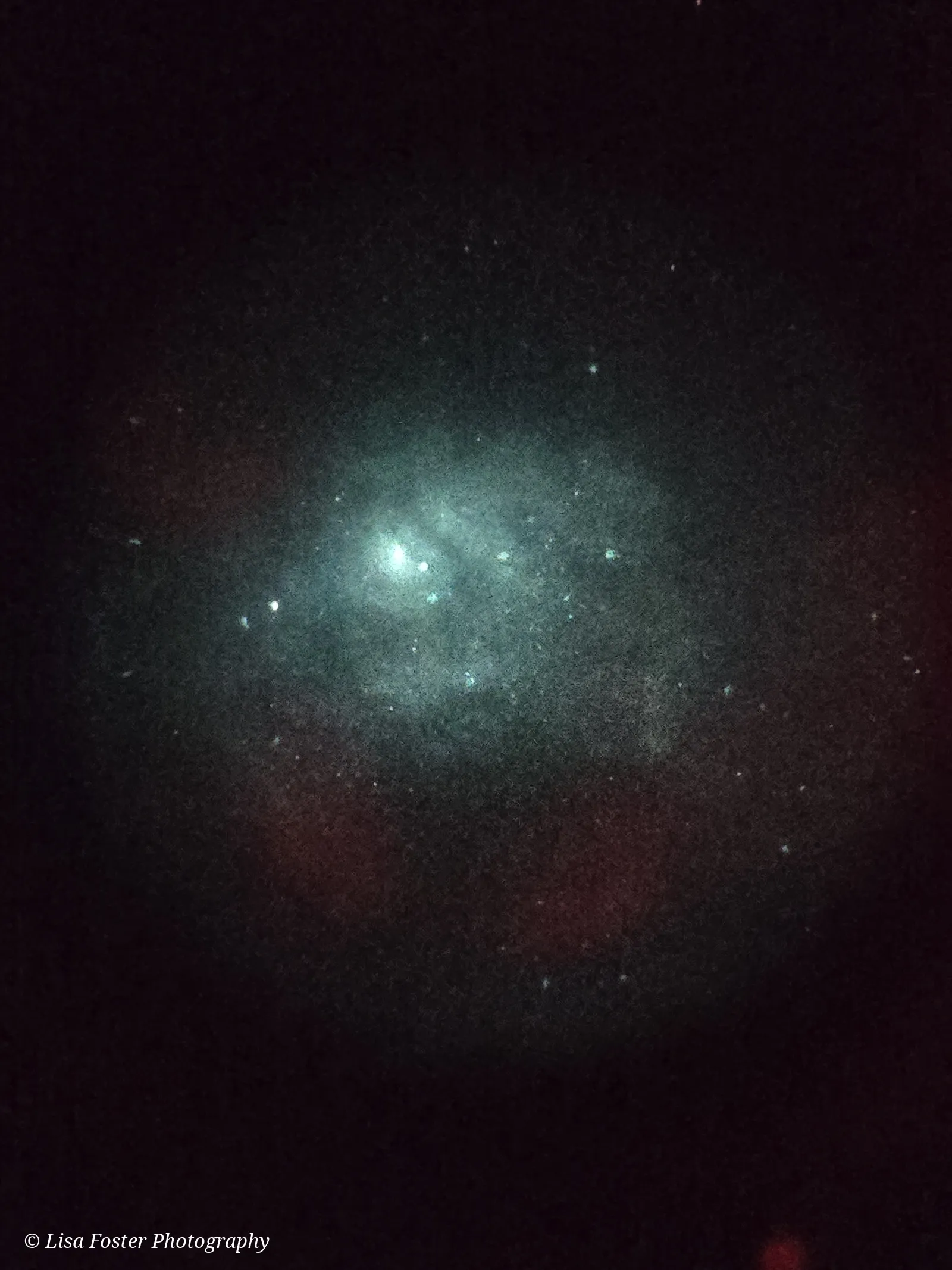 A soft, round eyepiece view with a fuzzy glow and a few stars