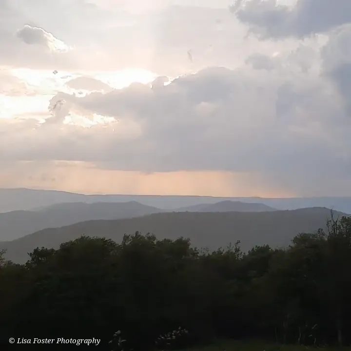 Layers of blue ridges under clouds with light breaking through