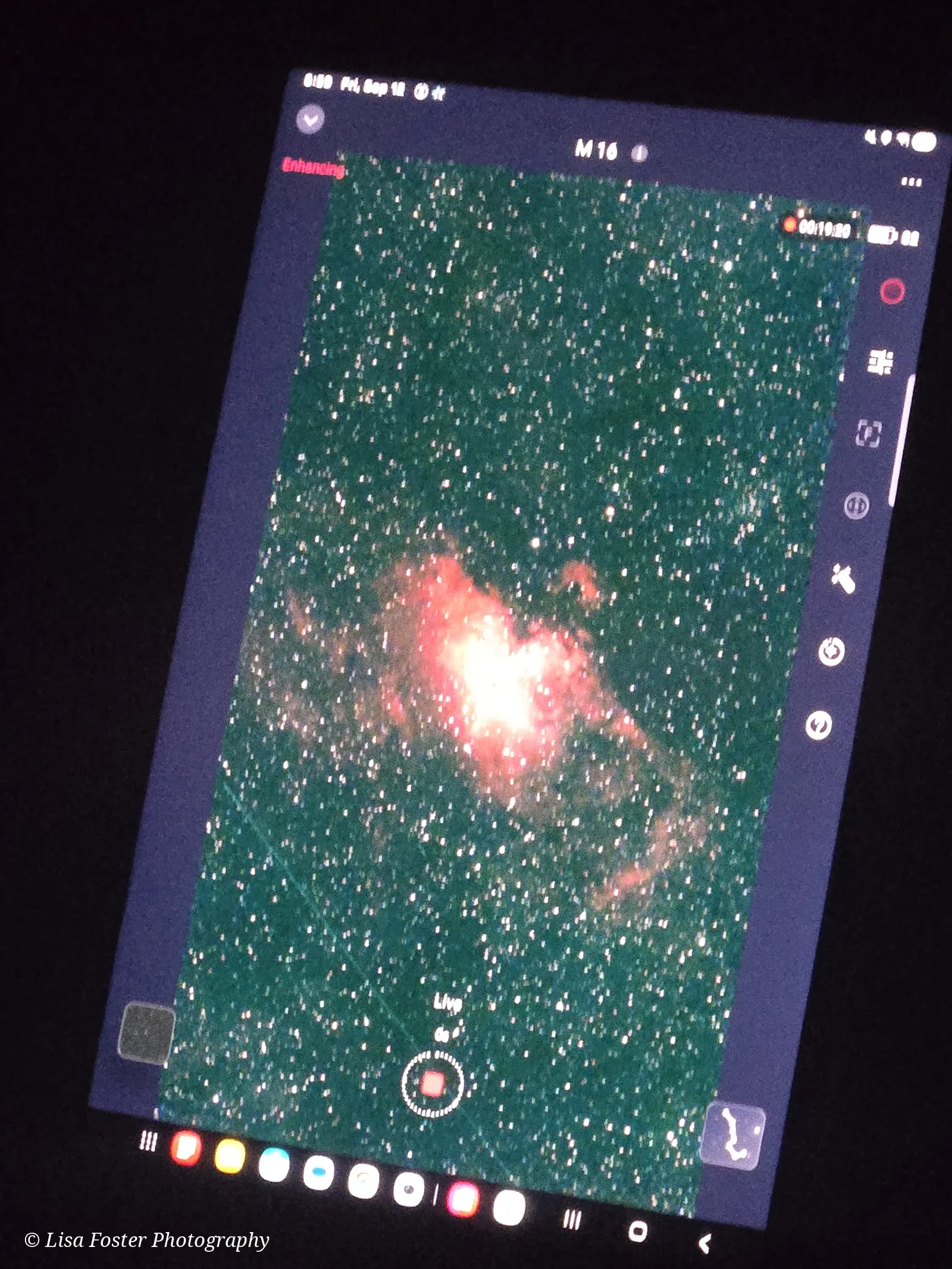 A tablet in the dark showing the Eagle Nebula, a red and orange cloud among thousands of stars, labeled M16