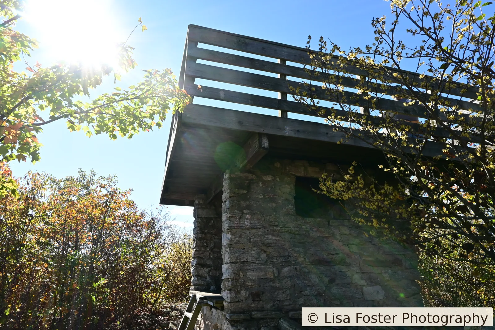 The Kennedy Peak lookout, a wood-and-stone tower with a railed deck and fall foliage at the railing.