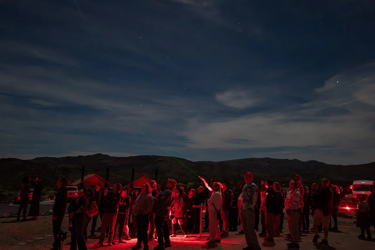 Visitors at a night astronomy program, lit only by dim red lights
