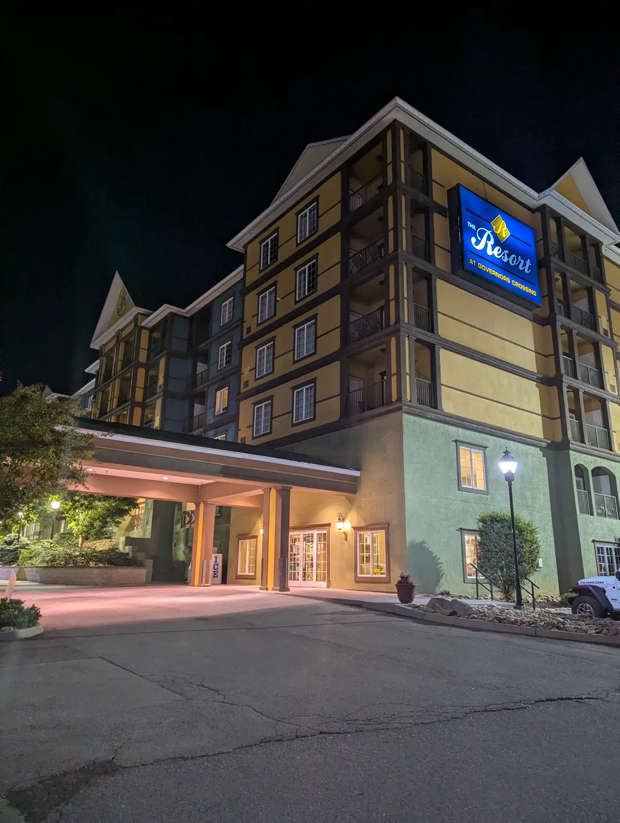 The Resort at Governor's Crossing lit up at night, with a covered entrance and the blue "The Resort at Governors Crossing" sign glowing on the building