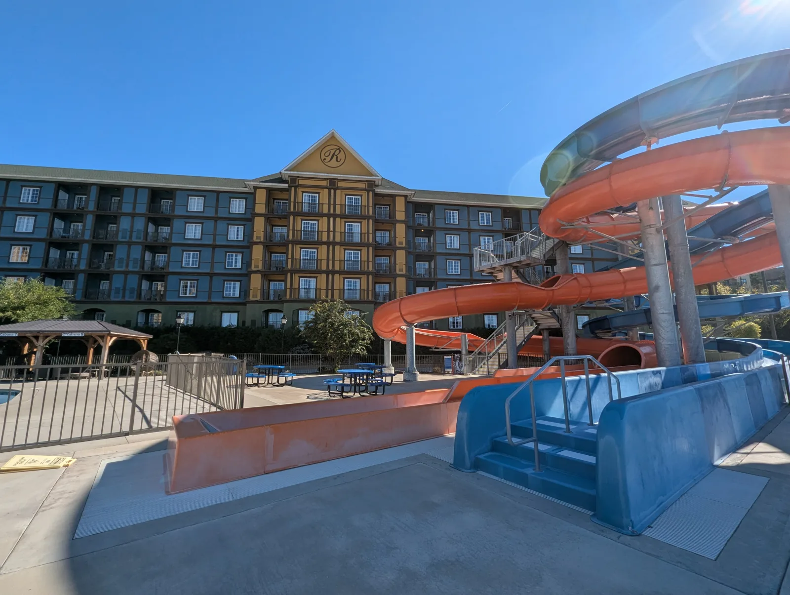 Orange and blue water slides curving down beside a resort building under a blue sky