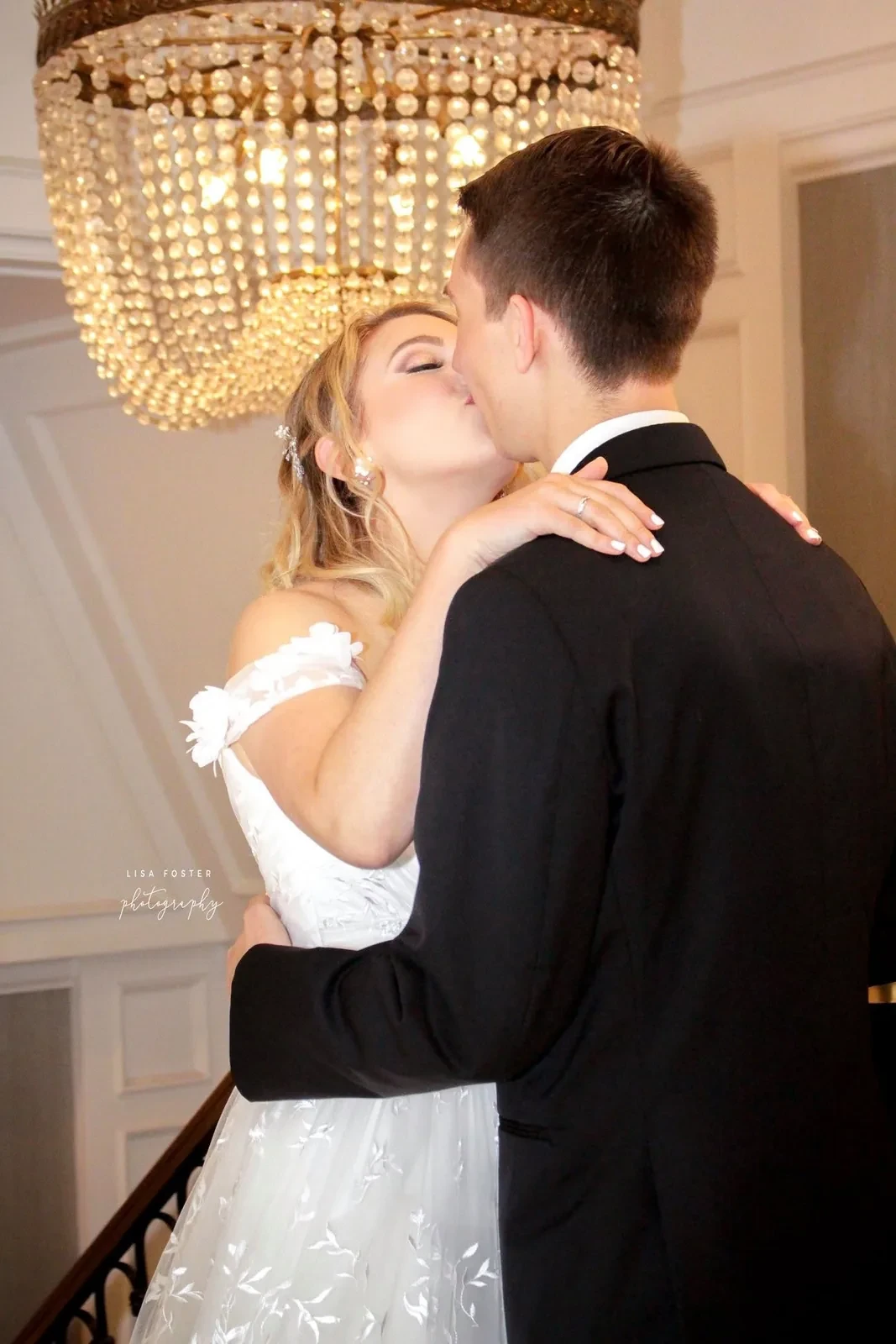Bride and groom kissing beneath a chandelier