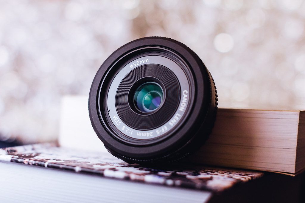 A small Canon prime lens resting on a stack of books