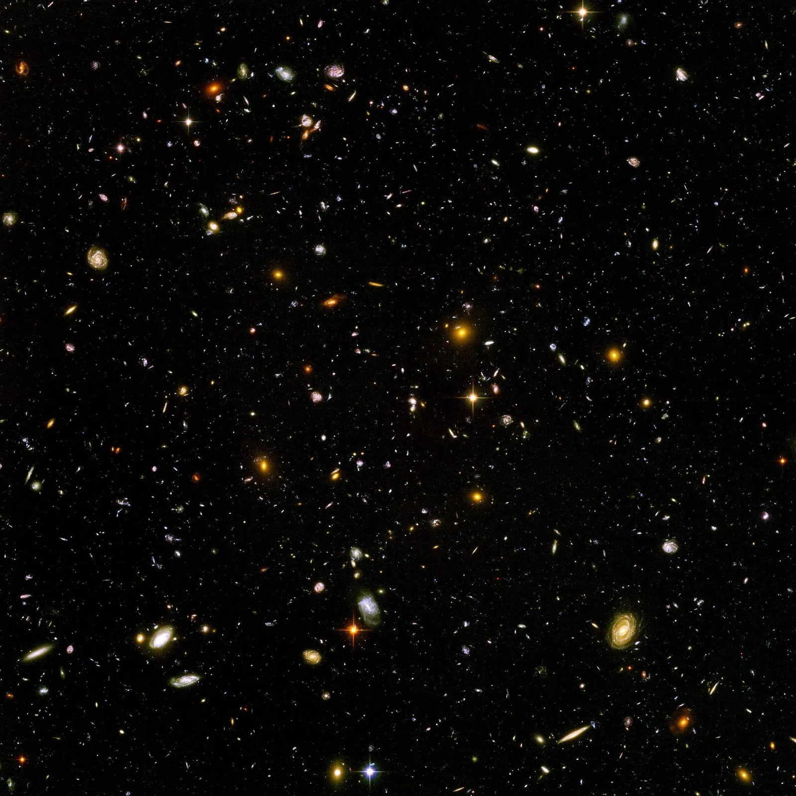 A field of thousands of galaxies of many colors and shapes against black space, seen by the Hubble Space Telescope