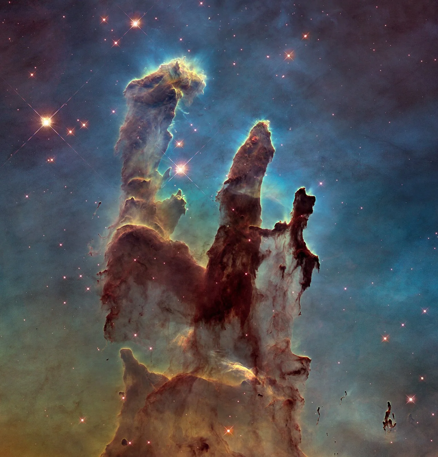 The tall, dusty Pillars of Creation in the Eagle Nebula, glowing in orange, brown, and blue