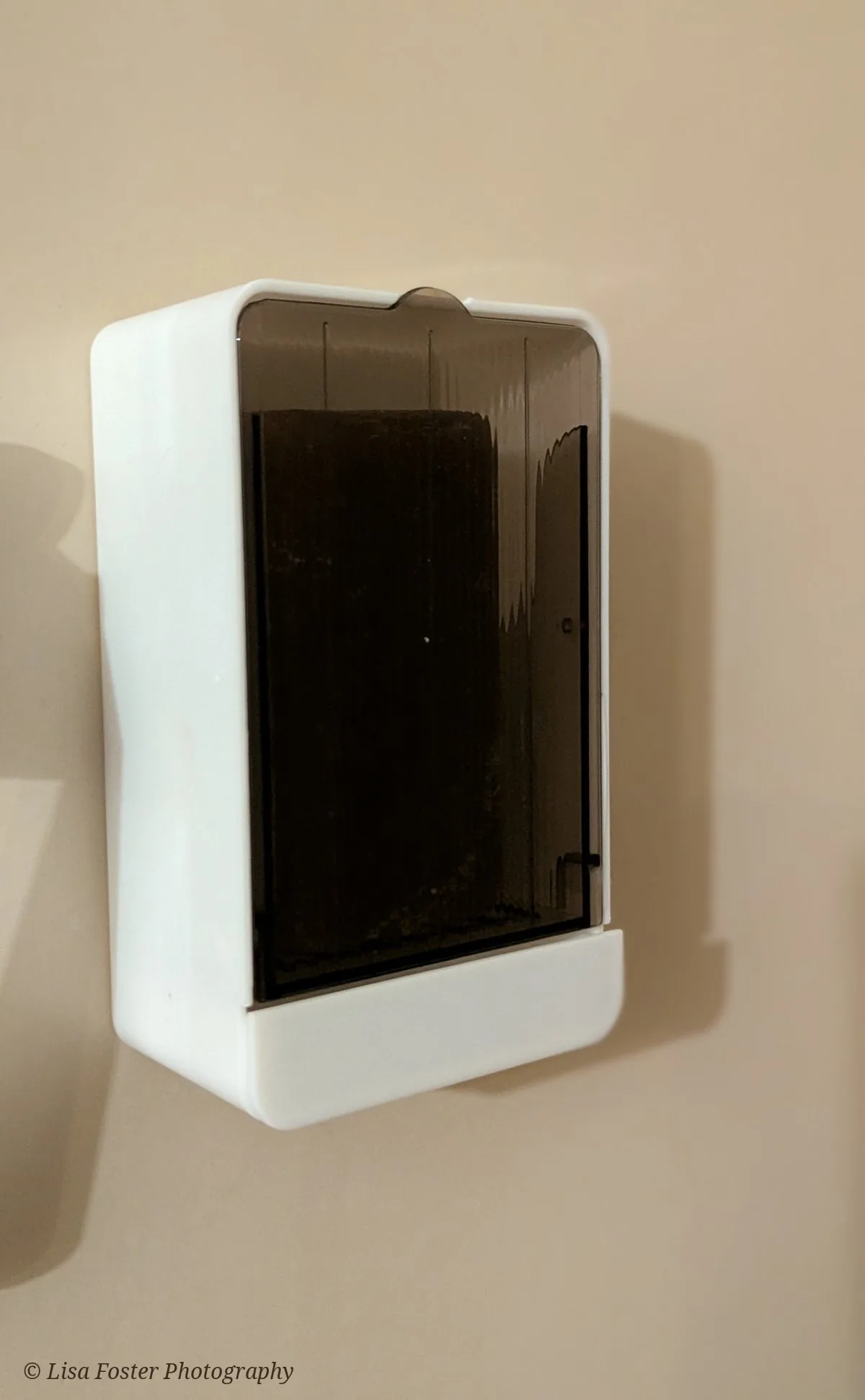 A closed white wall-mounted soap box with a smoky gray see-through lid, with the soap bar visible inside